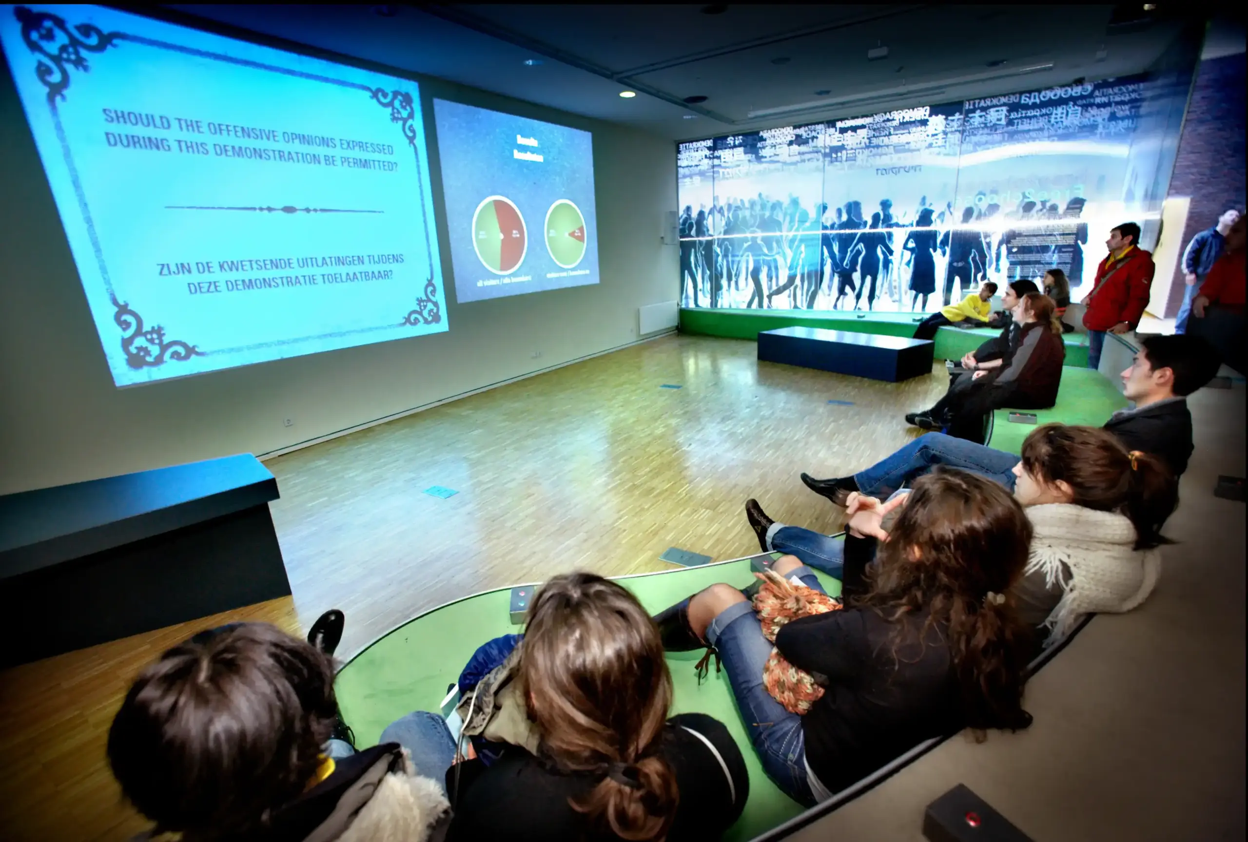 Groep mensen doen mee aan de debat installatie in het Anne Frank huis